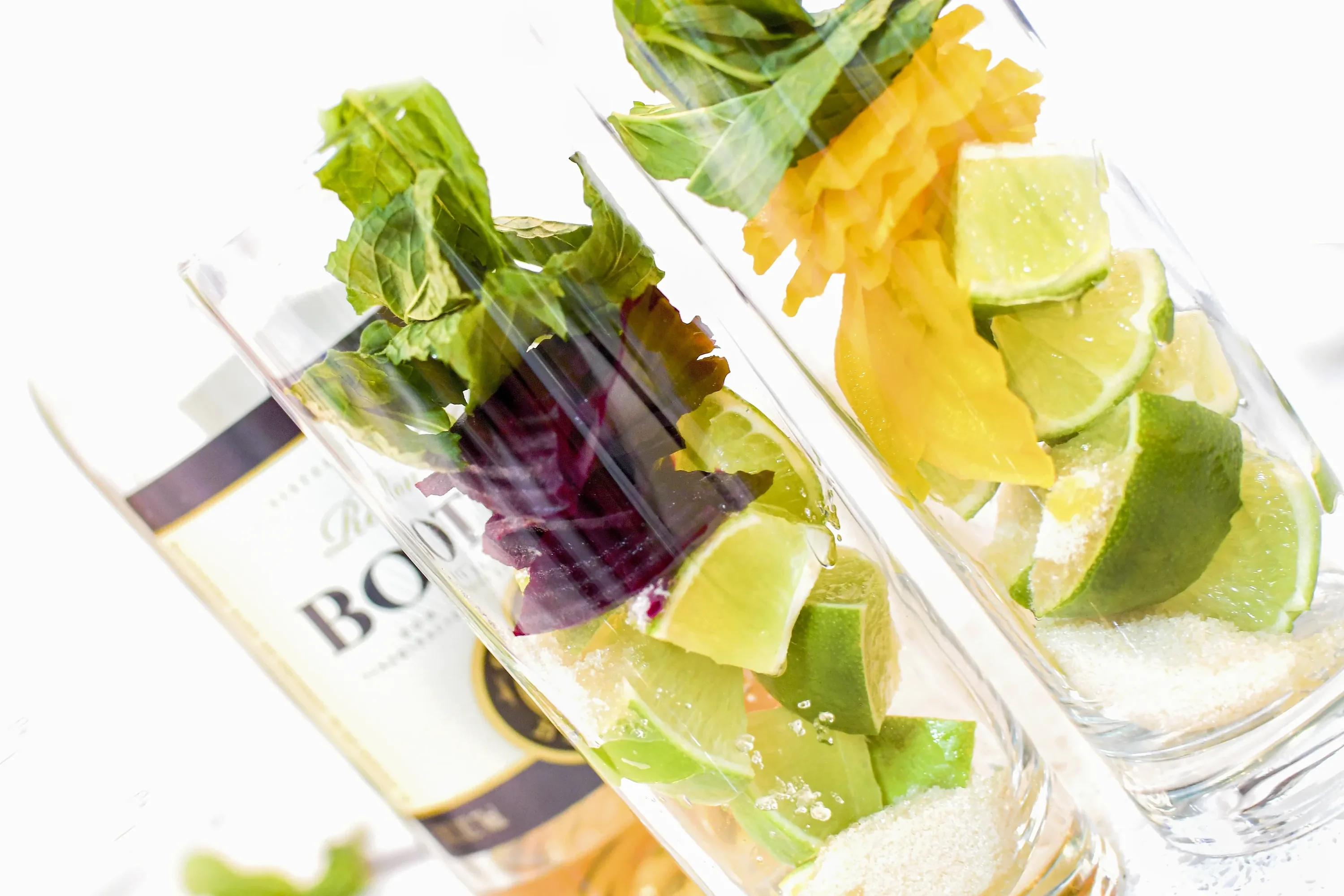 Red and golden beet Mojito ingredients arranged in two highball glasses