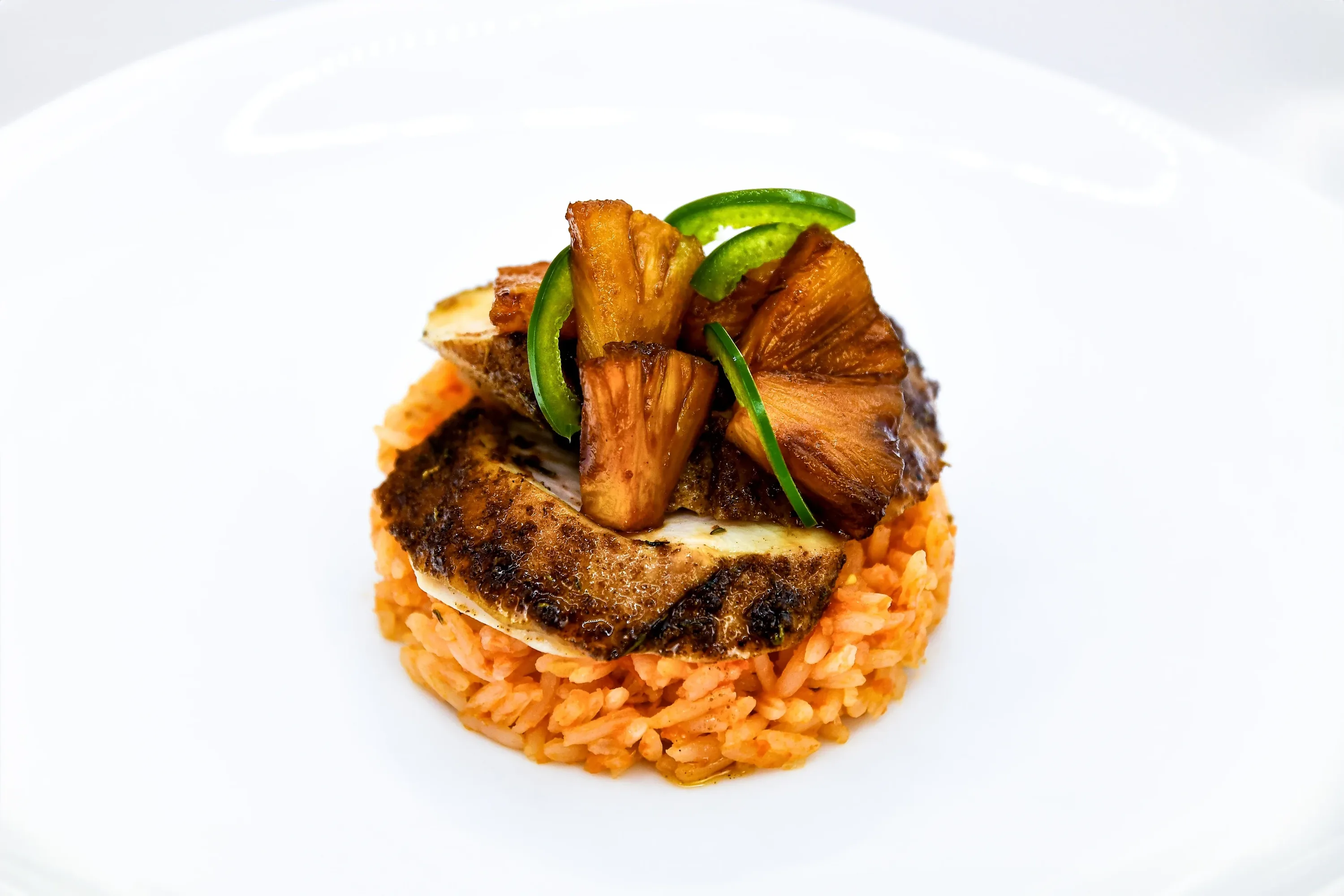Jerk chicken plated with red rice and pineapple