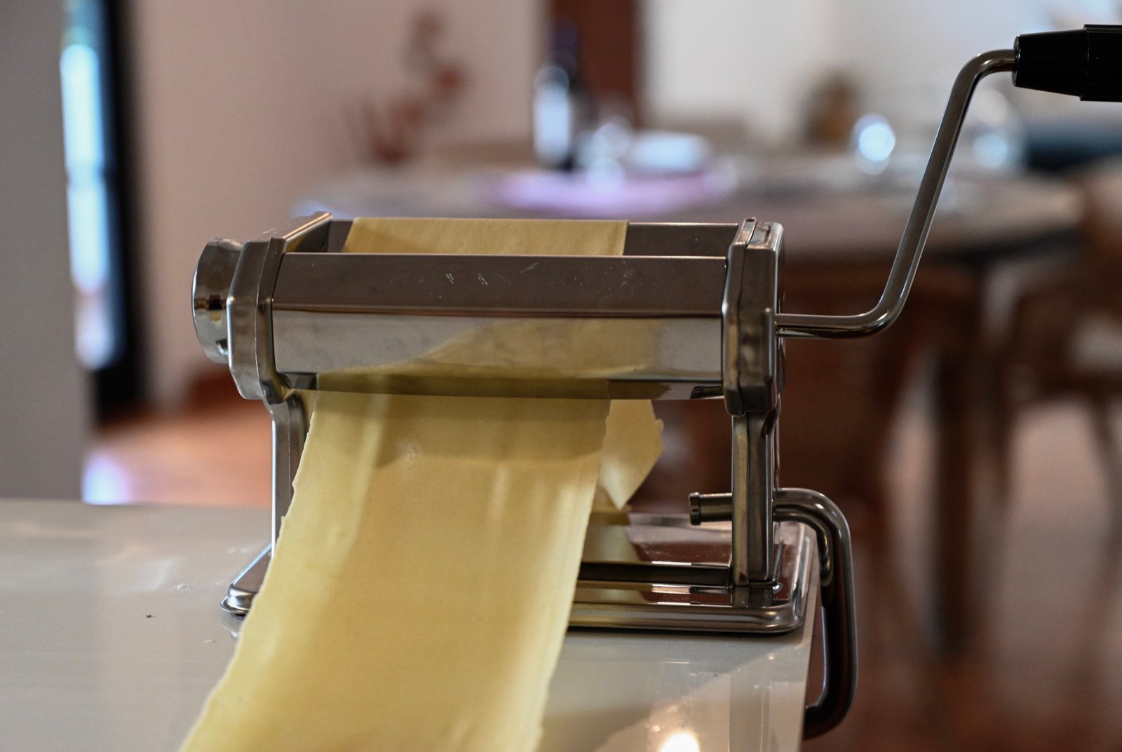 Fresh pasta dough rolling through a manual pasta machine