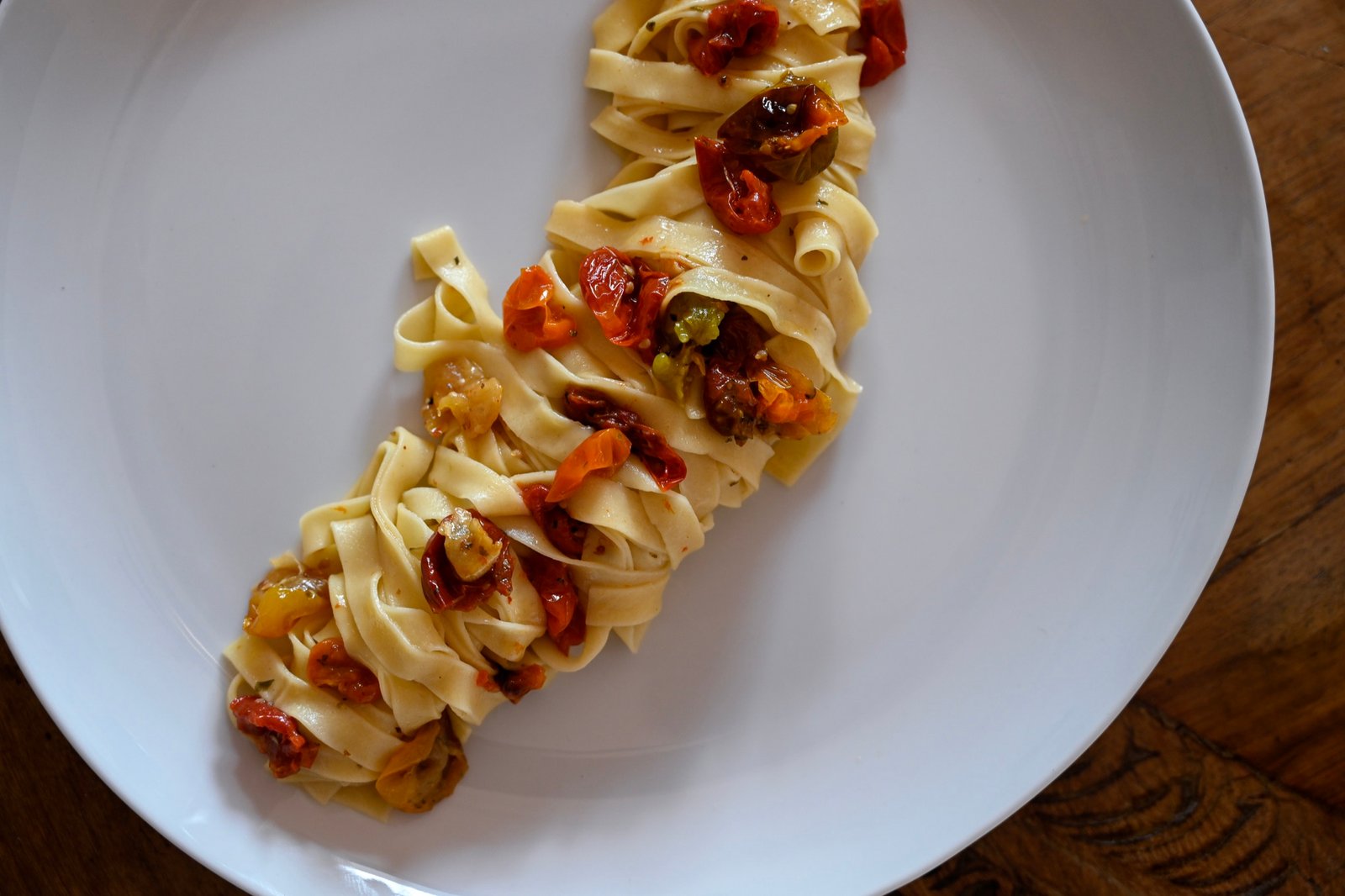 Fresh tagliatelle with roasted tomatoes plated on white porcelain